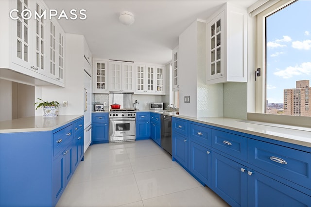 kitchen featuring glass insert cabinets, high quality appliances, blue cabinets, and light tile patterned flooring