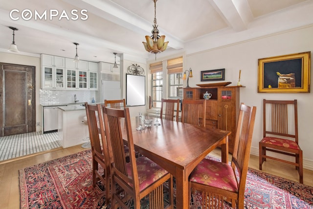 dining space with beam ceiling and light wood finished floors