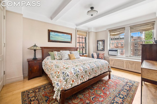 bedroom featuring radiator, light hardwood / wood-style flooring, and beamed ceiling