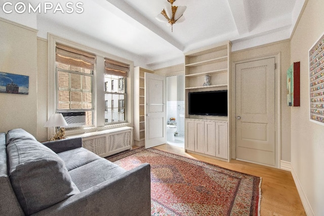 living room featuring built in features, cooling unit, radiator, and light hardwood / wood-style flooring