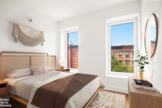 bedroom with multiple windows, baseboards, and wood finished floors