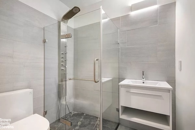 bathroom featuring toilet, a stall shower, tile walls, and vanity