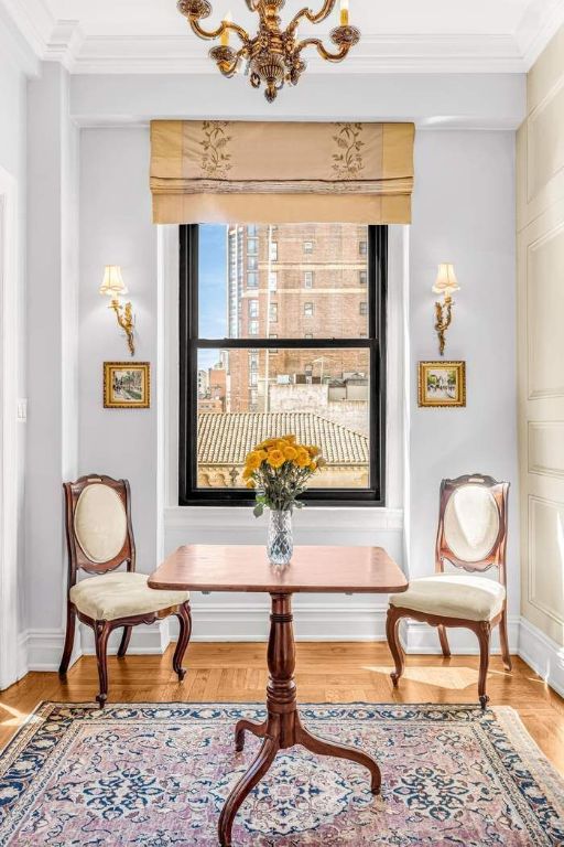 living area featuring hardwood / wood-style floors, ornamental molding, and a chandelier