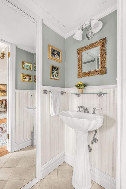 bathroom with tile patterned flooring, ornamental molding, and an inviting chandelier