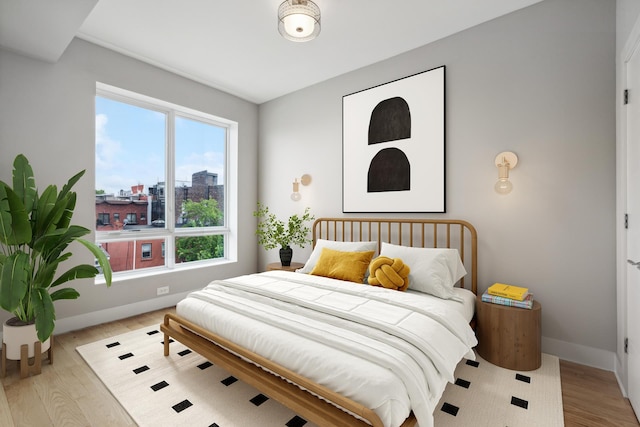 bedroom with a view of city, baseboards, and wood finished floors