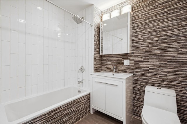 bathroom featuring tile walls, toilet, tiled shower / bath combo, vanity, and tile patterned flooring