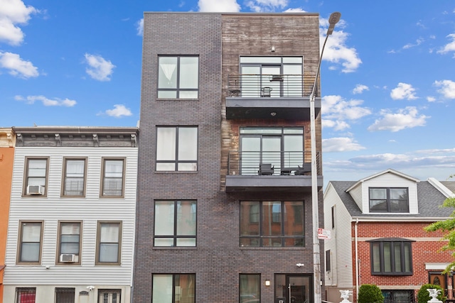view of front facade with brick siding and a balcony