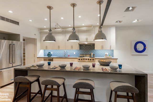 kitchen with decorative light fixtures, sink, high end appliances, and a center island