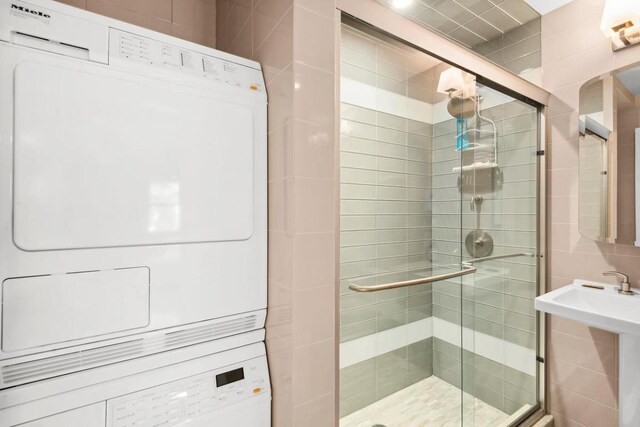 bathroom featuring enclosed tub / shower combo, sink, and tile walls