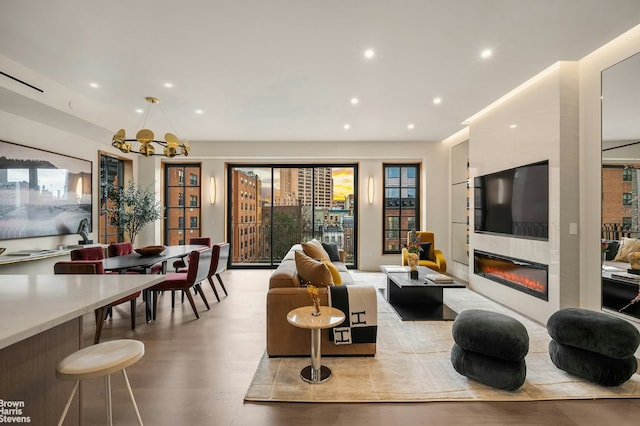 living room featuring a large fireplace, a notable chandelier, and light hardwood / wood-style flooring