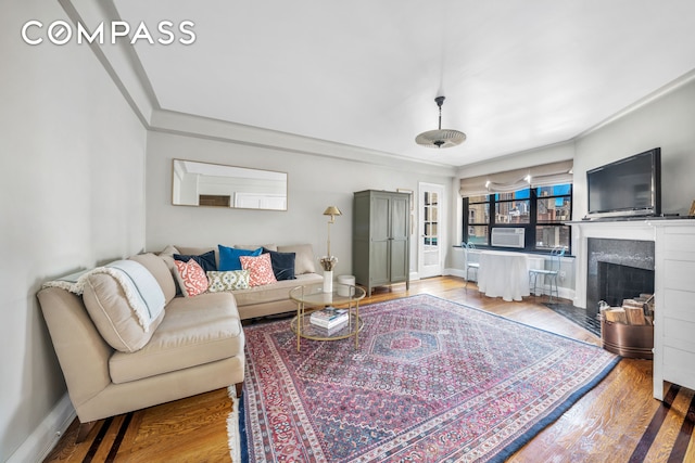 living room featuring a premium fireplace, baseboards, wood finished floors, and crown molding