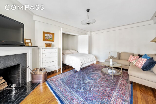 bedroom with wood finished floors and a fireplace with flush hearth