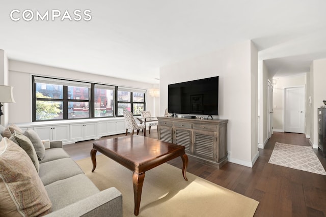 living room with baseboards, dark wood-style flooring, and a notable chandelier