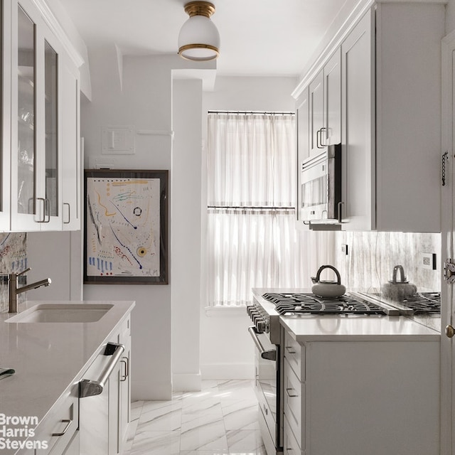 kitchen featuring appliances with stainless steel finishes, marble finish floor, white cabinets, and a sink