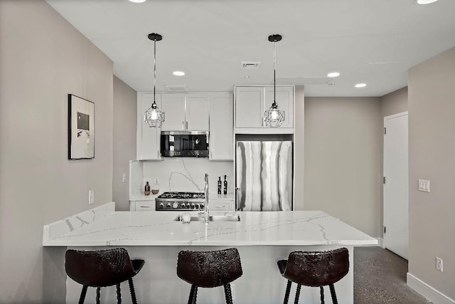 kitchen with white cabinetry, stainless steel appliances, a kitchen island with sink, and backsplash