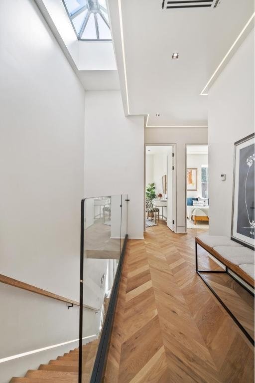 stairs with parquet flooring and a skylight