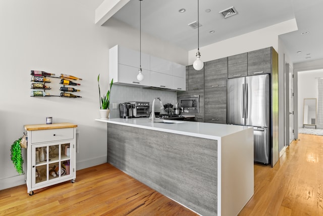 kitchen with visible vents, a peninsula, a sink, appliances with stainless steel finishes, and modern cabinets