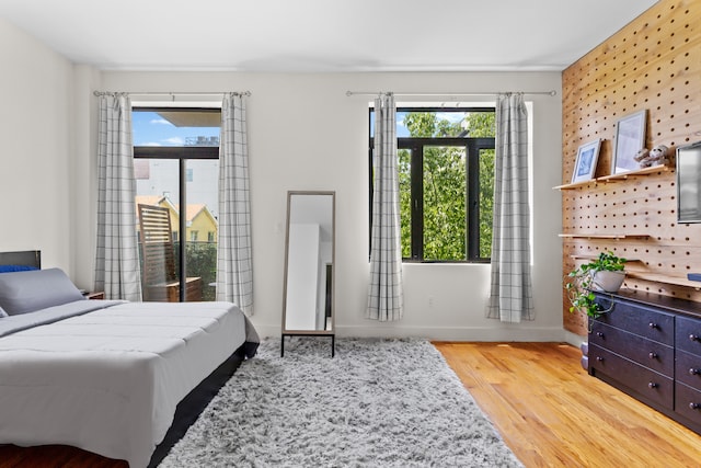 bedroom with multiple windows, wood finished floors, and baseboards