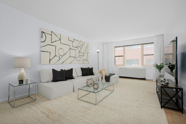 living area with radiator heating unit, wood finished floors, and baseboards