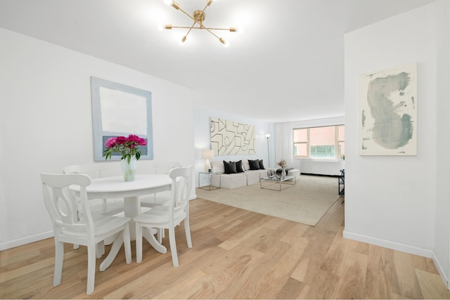 dining space featuring light wood-style floors, baseboards, and a notable chandelier