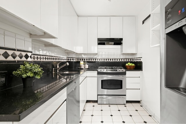 kitchen featuring dark countertops, appliances with stainless steel finishes, white cabinetry, a sink, and under cabinet range hood