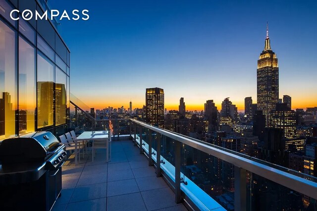 balcony at dusk with a view of city and area for grilling