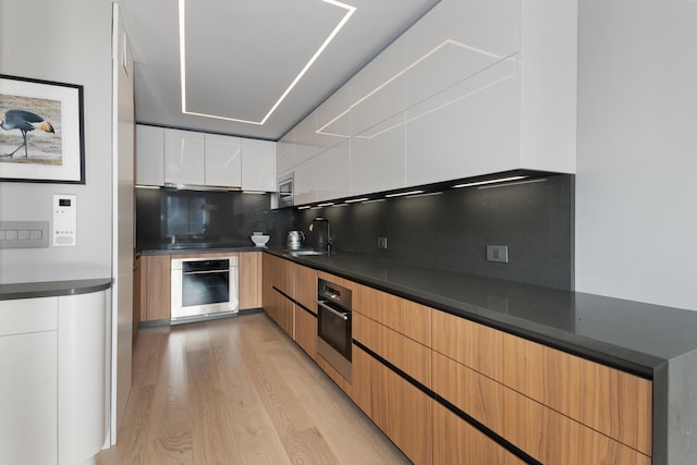 kitchen with dark countertops, modern cabinets, appliances with stainless steel finishes, and decorative backsplash