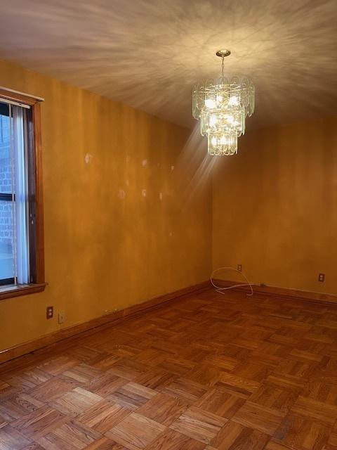 spare room featuring parquet floors and a chandelier