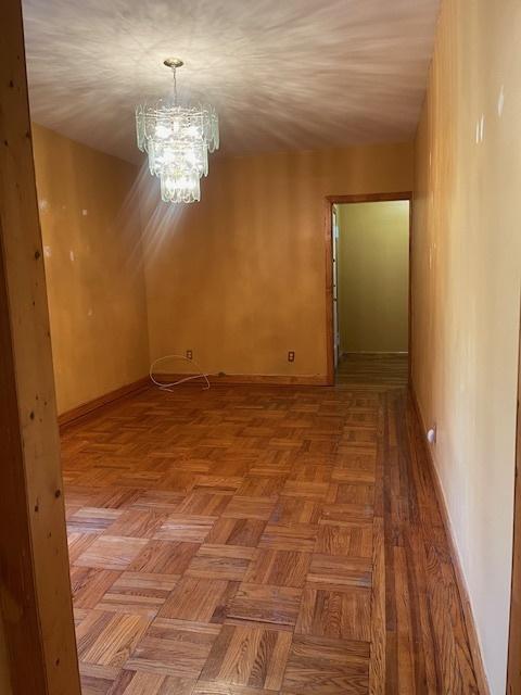 spare room featuring parquet flooring and a chandelier