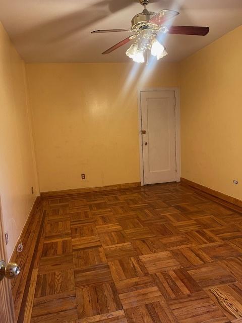 spare room featuring dark parquet flooring and ceiling fan