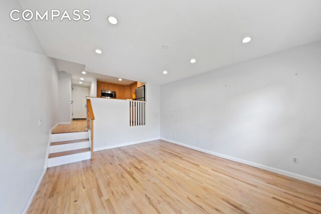 unfurnished living room featuring stairs, light wood-style flooring, recessed lighting, and baseboards