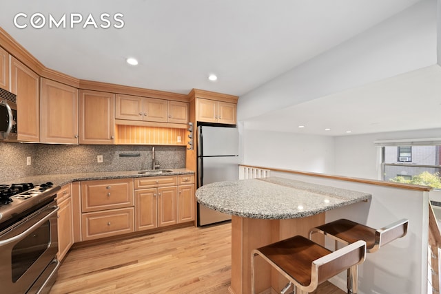 kitchen featuring a sink, backsplash, appliances with stainless steel finishes, and a breakfast bar