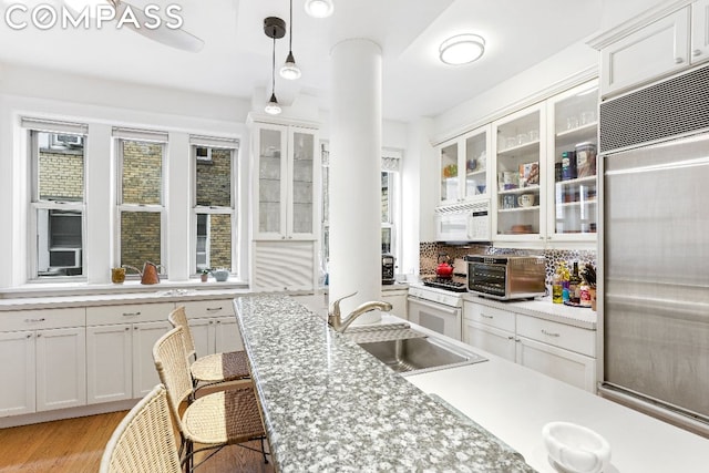 kitchen featuring white appliances, white cabinetry, sink, hanging light fixtures, and a breakfast bar