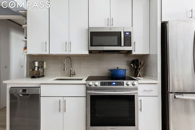 kitchen featuring appliances with stainless steel finishes, sink, white cabinets, and backsplash