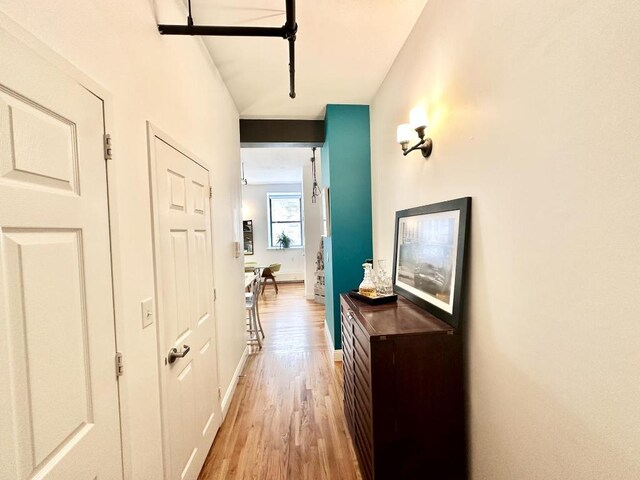 hall with light wood-type flooring and baseboards