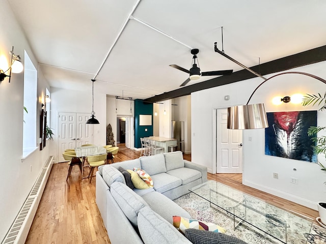 living area featuring baseboard heating, light wood-style floors, a ceiling fan, and baseboards