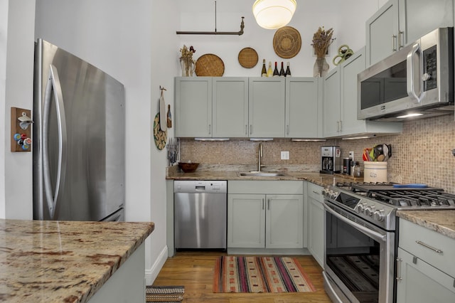 kitchen featuring stainless steel appliances, light wood finished floors, a sink, and backsplash
