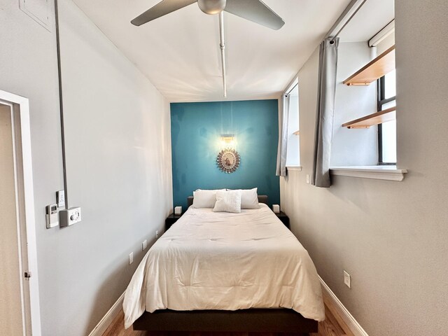 bedroom with a ceiling fan, baseboards, and wood finished floors