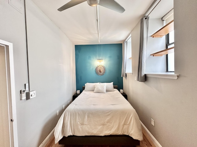 bedroom featuring wood finished floors, baseboards, and a ceiling fan