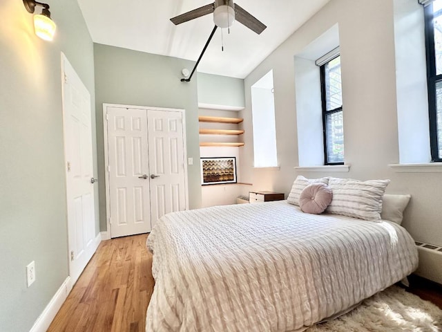 bedroom featuring a closet, baseboards, ceiling fan, and light wood finished floors