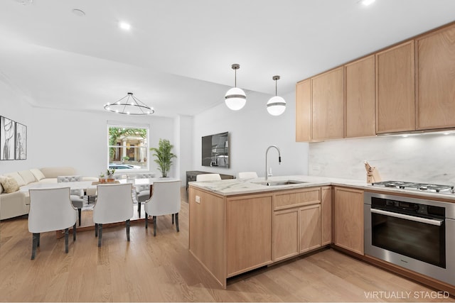 kitchen with stainless steel appliances, light brown cabinets, a sink, and under cabinet range hood