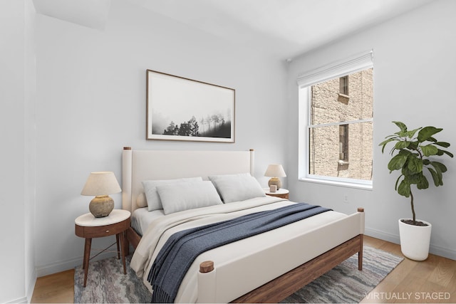 bedroom with baseboards, wood finished floors, and multiple windows