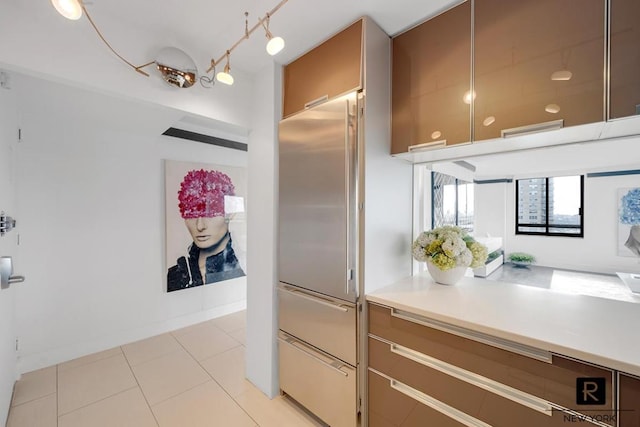 kitchen featuring light tile patterned floors, baseboards, light countertops, and built in fridge