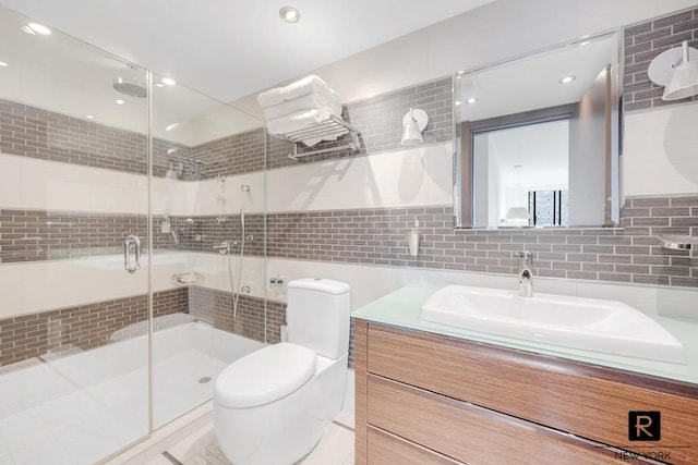 full bathroom featuring tile walls, decorative backsplash, toilet, a stall shower, and vanity