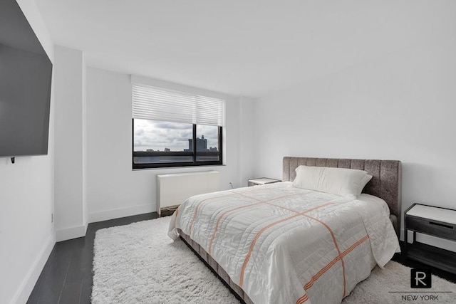 bedroom with dark wood-type flooring, radiator heating unit, and baseboards