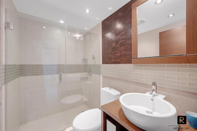 full bathroom with a stall shower, visible vents, toilet, vanity, and tile walls