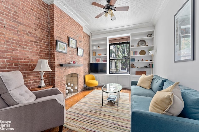 living room with ceiling fan, brick wall, ornamental molding, and hardwood / wood-style floors