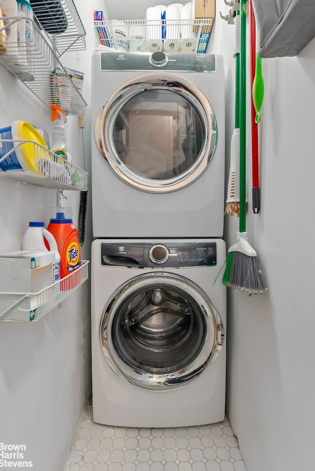 laundry area featuring tile patterned floors, stacked washer and clothes dryer, and laundry area