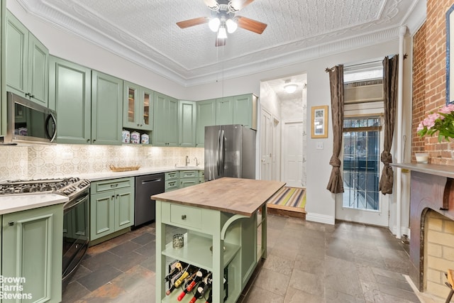 kitchen featuring green cabinetry, open shelves, appliances with stainless steel finishes, and stone tile floors