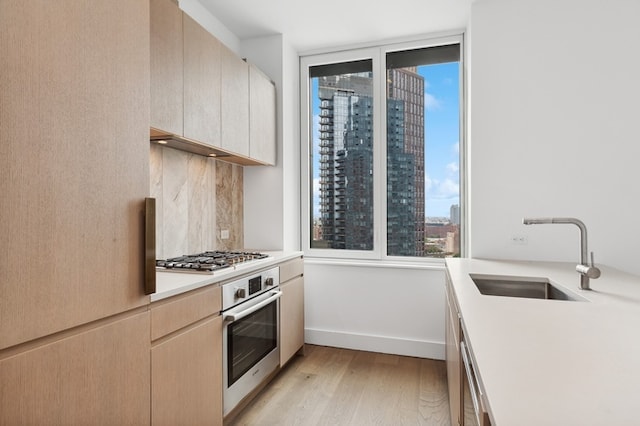 kitchen with a view of city, light wood-style flooring, a sink, stainless steel appliances, and light countertops